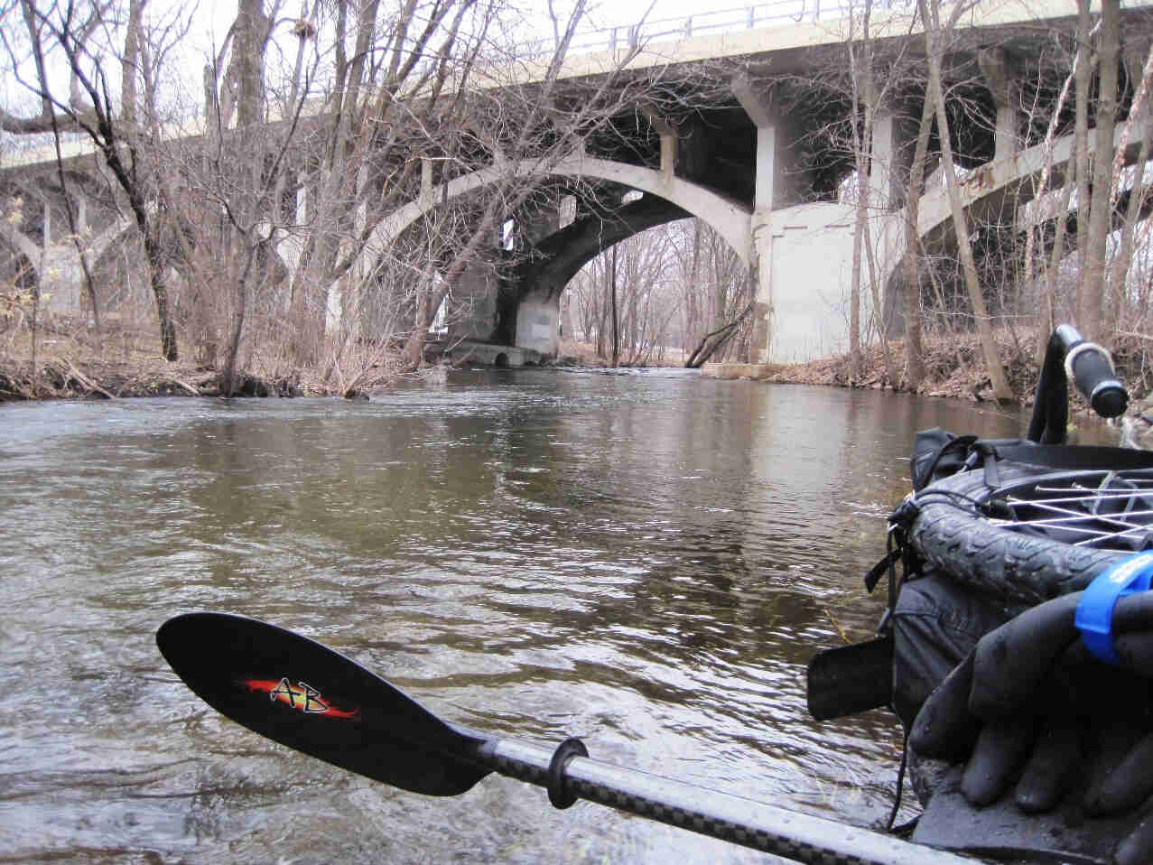 Front view from a raft with a disassembled Surly Travelers check bike, floating down a river and approaching a bridge